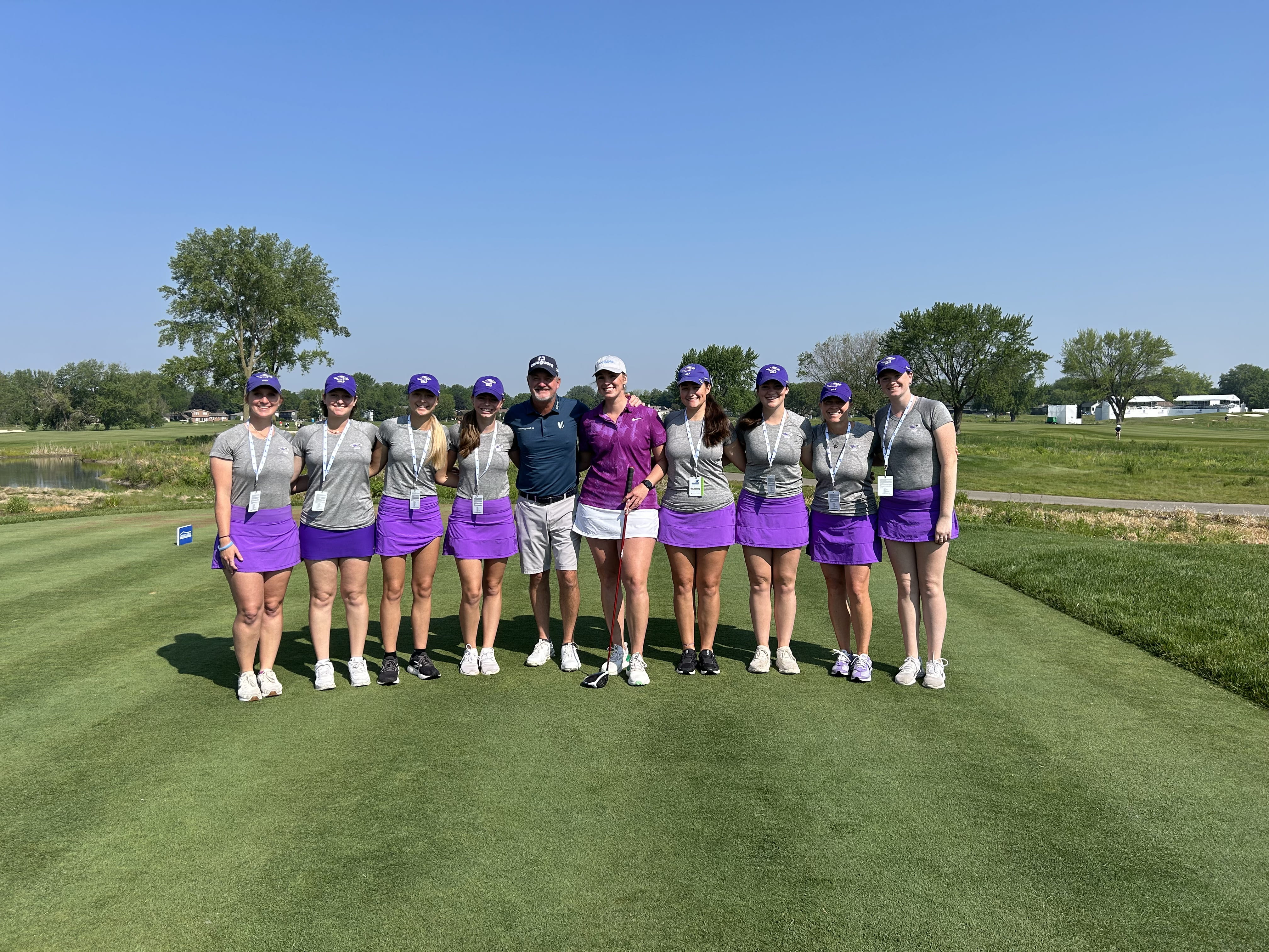 Make-A-Wish recipient Natalie Kammer and her UW-Whitewater golf team stand smiling with PGA Tour Champion Jerry Kelly on a golf course.